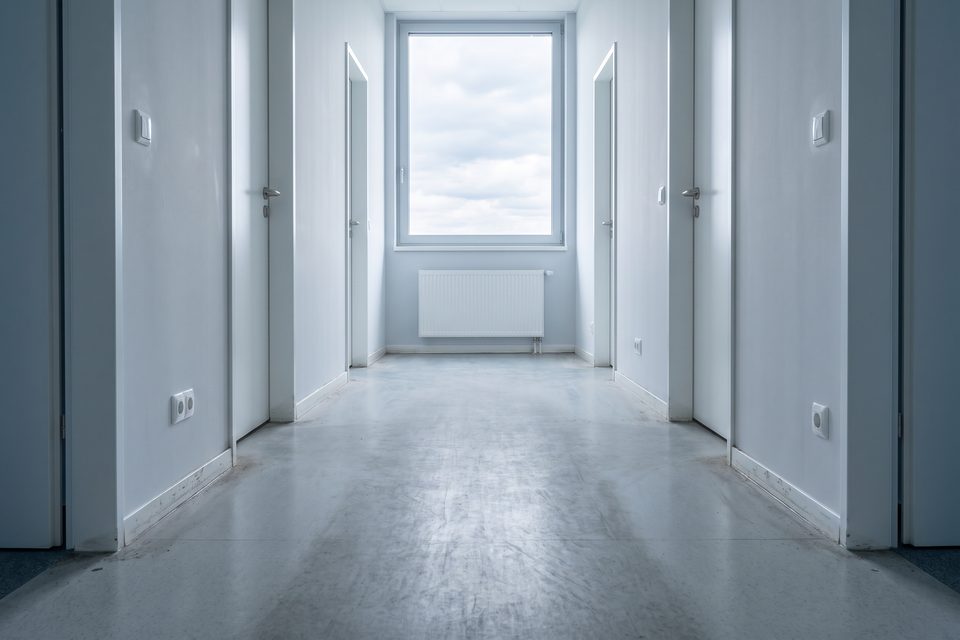 Bürogang vorher mit Grauschleier, Laufstraße und dunklen Kanten, nachher mit gleichmäßig seidenmattem, sauberem Boden